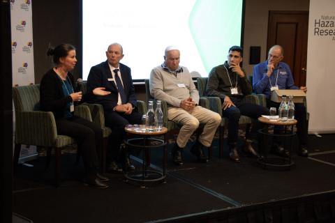 Panel of five people sitting on stage
